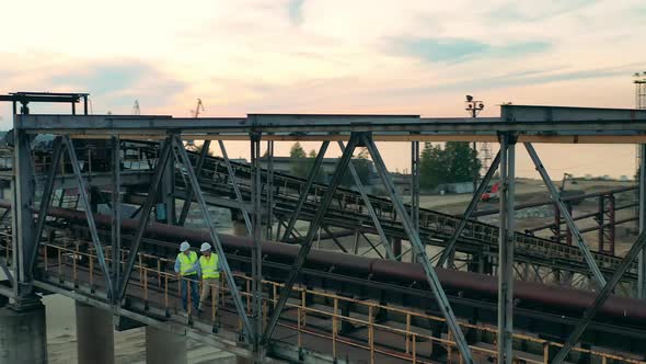 Industrial Construction in the Port with Two Engineers Walking Along It