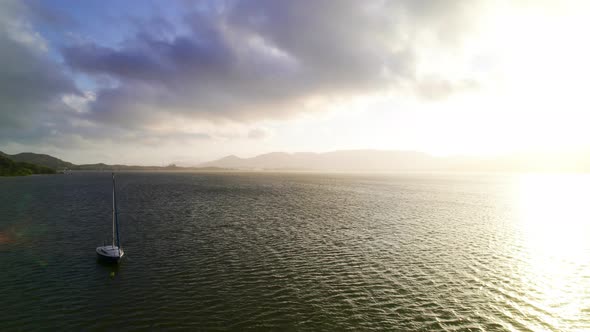 A Floating Boat in the Ocean Meets the Sunset with the Mountains on the Horizon