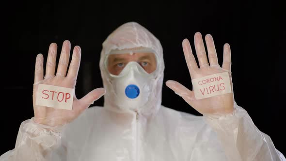 Man Wearing Protective Suit Showing Palms with Inscription