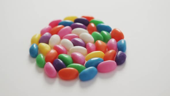 Video of close up of multi coloured sweets forming circle over white background