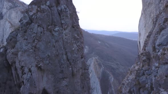 Ascending aerial view of peaks in Turda Gorge, Romania reveals climber on top on small rocky summit