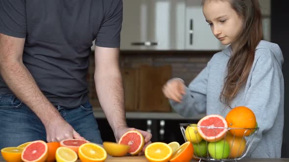 Father and Daughter are Making Fresh Citrus Juice at Home at the Kitchen