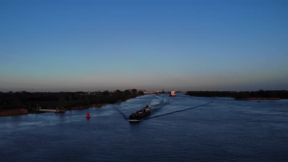 Barge Ship Cruising On Canal River With Speeding Motorboat Overtake During Bluehour In Oude Maas, So