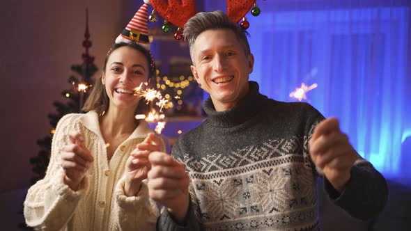 Happy Family Portrait Woman in Festive Elf Cap and Man in Red Reindeer Antlers Headband Looking at