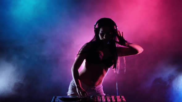 Girl DJ Dancing Develop Her Hair Behind Her Multicolored Lights and Smoke. Silhouette