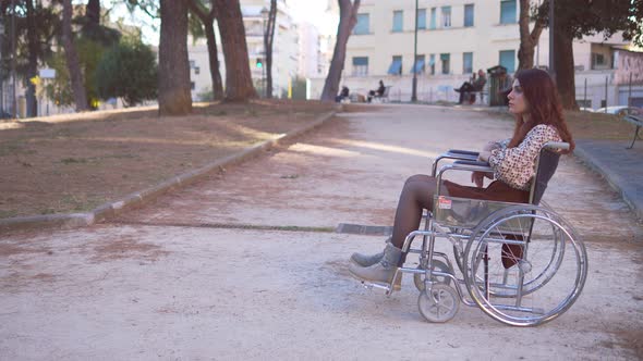 solitude, disability- young woman using wheelchair alone at park looks up