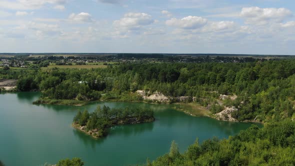 Aerial View of a lake with Beautiful Water in a Quarry Surrounded by Forest, Small Town and Mining O