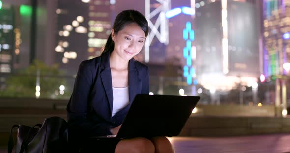 Businesswoman working on notebook in city at night