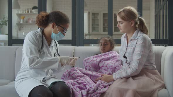 Female Doctor Measuring Temperature of Iil Girl