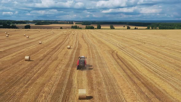 A tractor with a baler collects straw into bales.