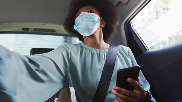 African american businesswoman with face mask using smartphone