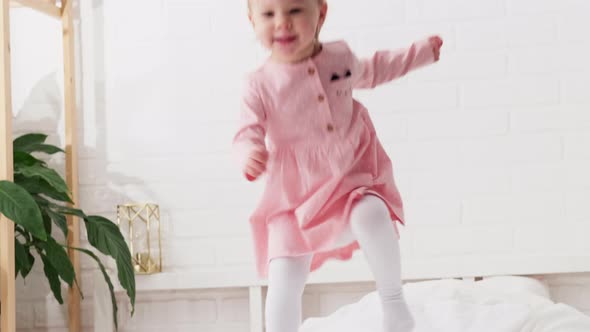 Happy Child Girl Having Fun Jumping and Playing Funny Active Game in Parents Bed Bouncing Fooling