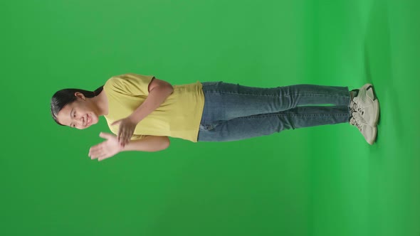 Full Body Of Side View Of Young Asian Kid Girl Clapping Her Hands In The Green Screen Studio