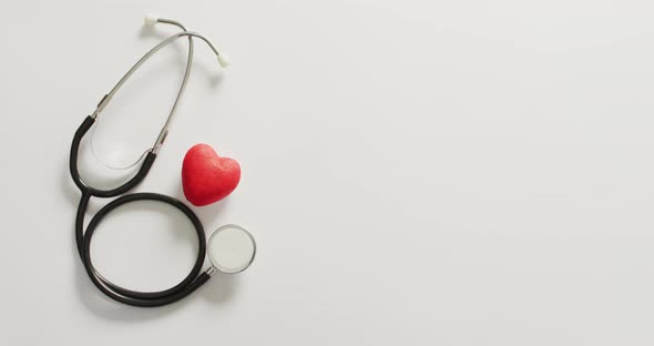 Video of close up of stethoscope with heart on pink background