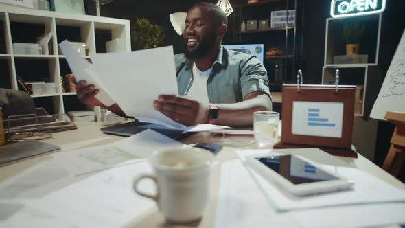 Portrait of Smiling Afro Business Man Satisfying with Documents at Workplace.