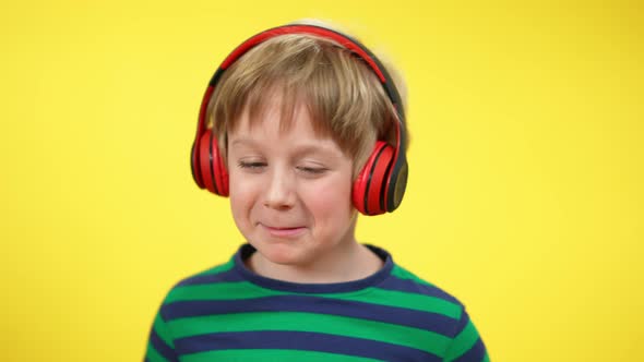 Closeup of Cheerful Charming Caucasian Boy in Headphones Singing and Dancing at Yellow Background