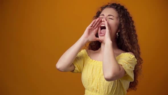 Young Curly Haired Woman Shouting Against Yellow Background