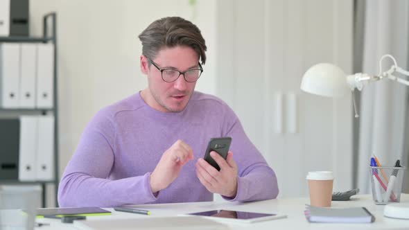 Middle Aged Man Celebrating Success on Smartphone 