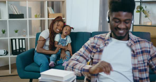 Mother with Daughter Waving to Father that Working on laptop