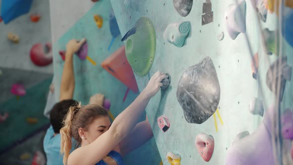 Girl and Guy Sportspeople Moving Up Climbing Wall Indoors Training Together