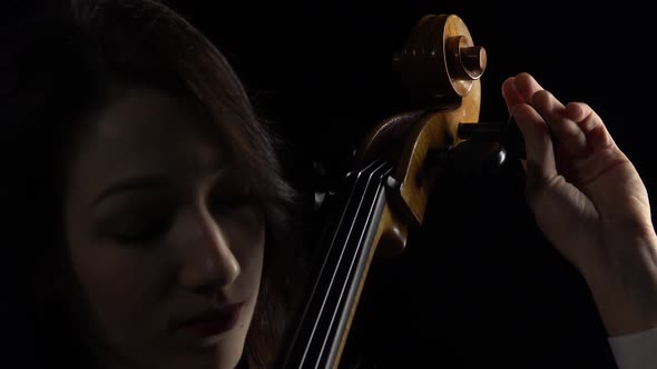 Musician Tunes a Cello. Black Background. Close Up