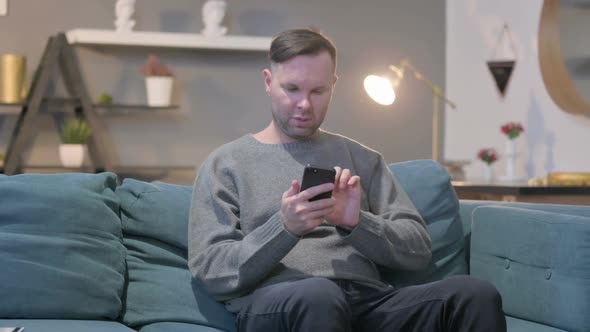 Casual Man Having Loss on Smartphone at Home