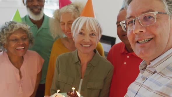 Portrait of happy senior diverse people at birthday party with cake at retirement home