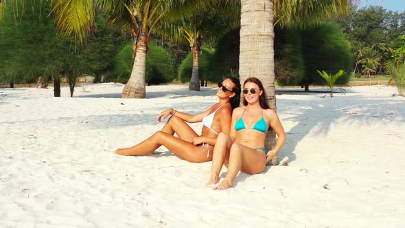 Beautiful beauty models relaxing in the sun at the beach on clean white sand and blue background 4K