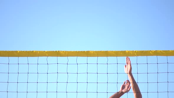 A man spiking a beach volleyball