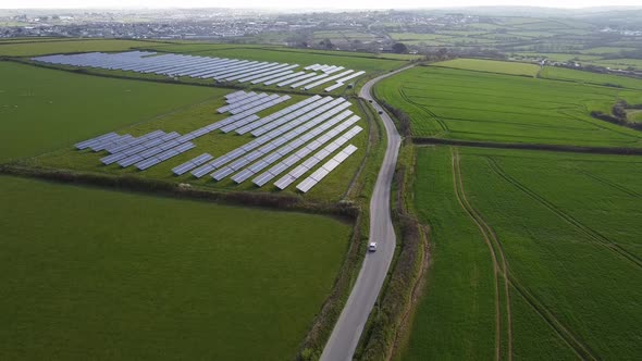 Distant shot looking down on solar farm panels green fields background