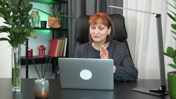 Successful businesswoman in earphones is communicating by video call