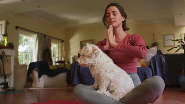 Caucasian woman practicing yoga with her pet dog at home