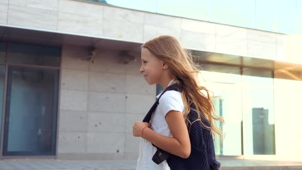 Close Up of Happy Little Child Schoolgirl with Long Blond Hair and Large Backpack Goes To Lesson on
