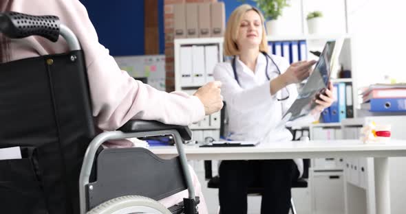 Doctor Examines Xray of Spine with Patient in Wheelchair