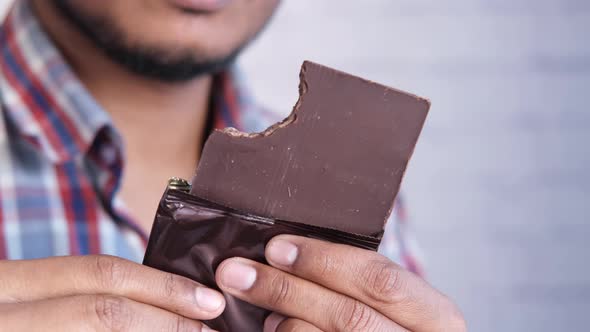 Young Man Eating Dark Chocolate Close Up