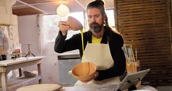 Male potter pouring watercolor in bowl