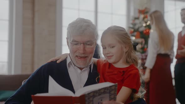 Grandad Reading a Book with Granddaughter Everyone Preparing for Christmas Eve
