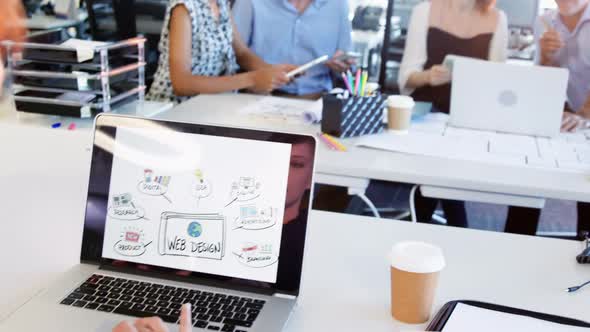 Female executive having coffee while working over laptop