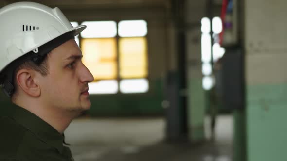 Inspector in Helmet Walks Along the Corridor of an Old Building Looks Around