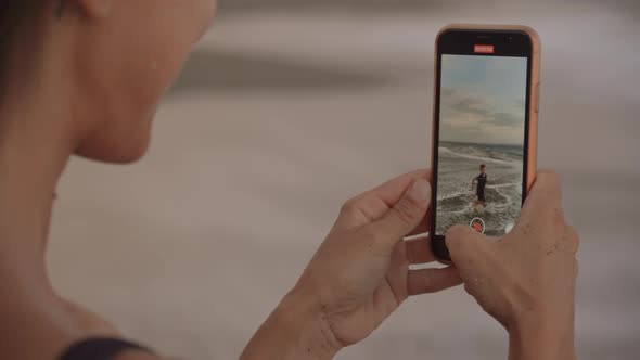 Woman Recording Video of Her Son in Sea at Sunset