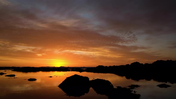 Golden sunset with sky on fire, reflections off water surface, warm tones