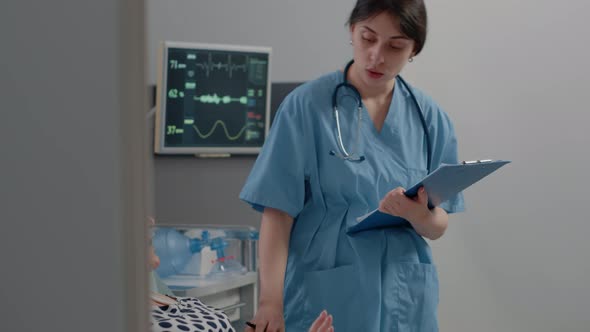 Nurse Taking Notes on Medical Files for Examination with Patient