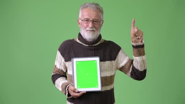 Handsome Senior Bearded Man Wearing Warm Clothing Against Green Background