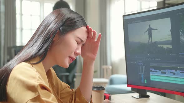 Tired Asian Female Video Editor Works With Footage And Sound On Her Personal Computer In Office
