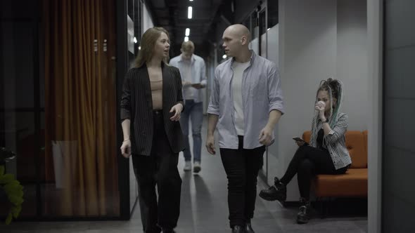 Wide Shot of Confident Young Man and Woman Walking in Office Talking