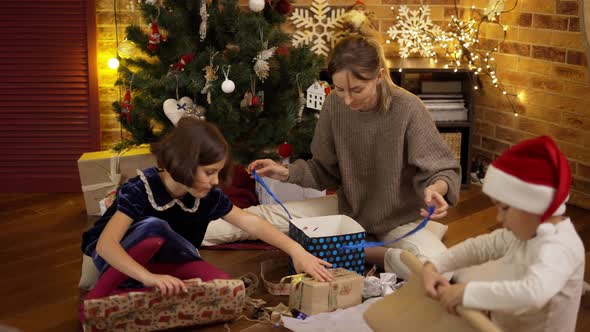 Mother and Kids Wrapping Christmas Present on the Floor