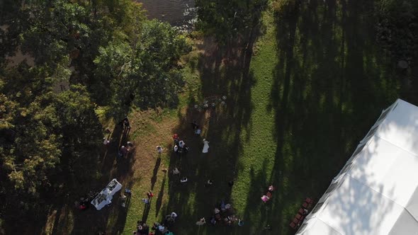 The Camera Flies High Above the Resting People on the Lawn on the River Bank