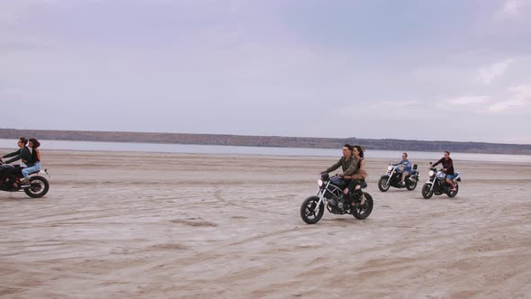 Group of Young People Riding Motorbikes on the Beach in Evening