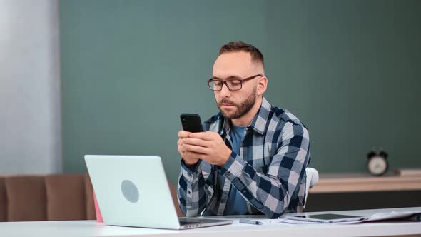 Focused Business Male Chatting Use Smartphone Sitting at Modern Workplace