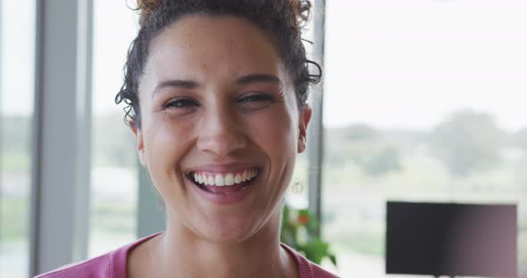 Portrait of smiling biracial creative businesswoman in modern office interior